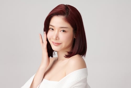 young asian woman with clean fresh skin on grey background