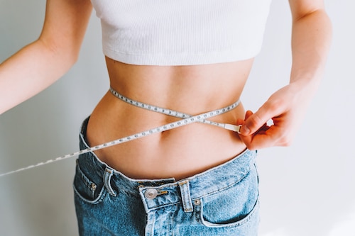 Slim woman measuring her waist after CoolSculpting