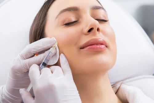 Close up portrait of young smiling pretty woman having botox rejuvenation procedure