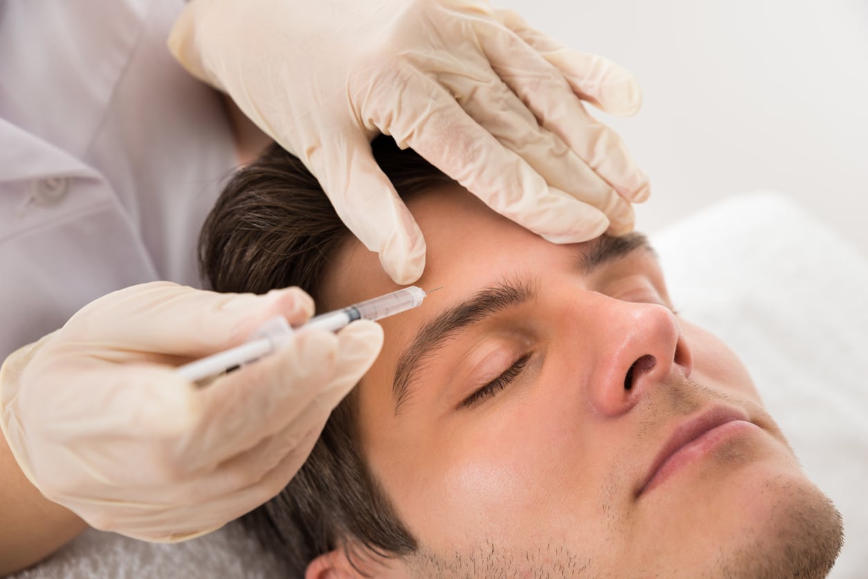 Gloved hands injecting wrinkle relaxer into man's face, concept of cosmetic treatment and anti-aging skincare